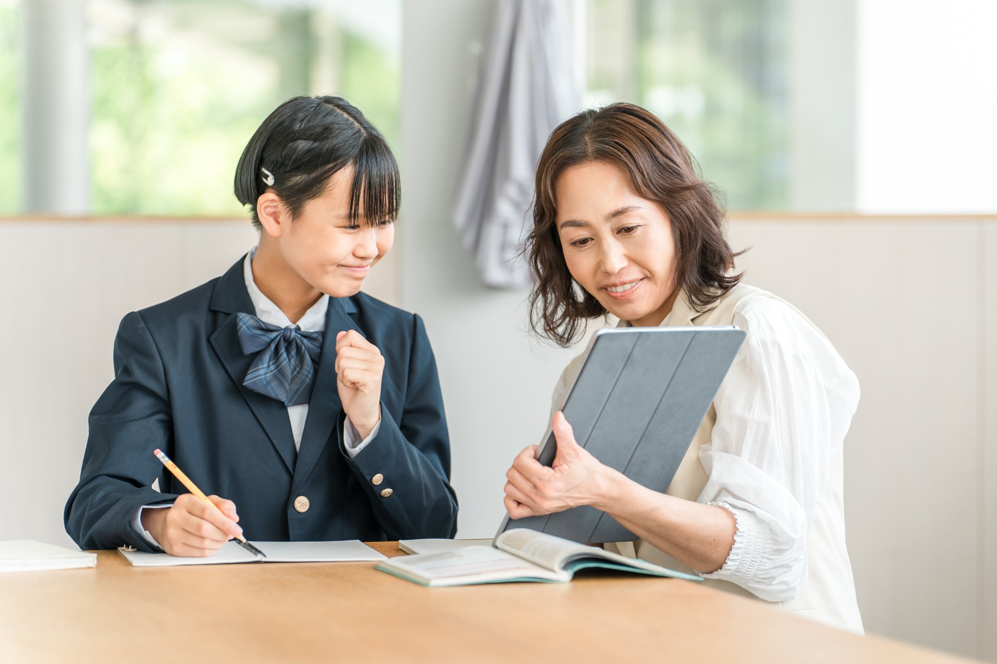 制服の女子生徒と女性教師がタブレットで学習